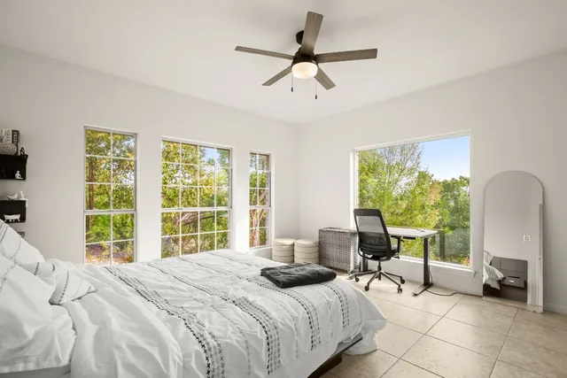 a bedroom with a bed a large window and a chandelier