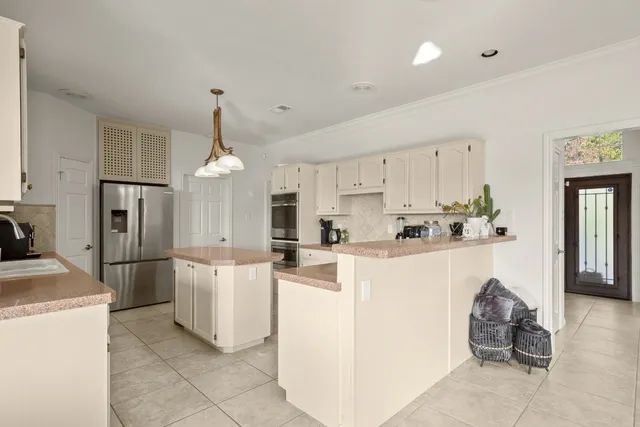 a kitchen with stainless steel appliances kitchen island a refrigerator sink and cabinets