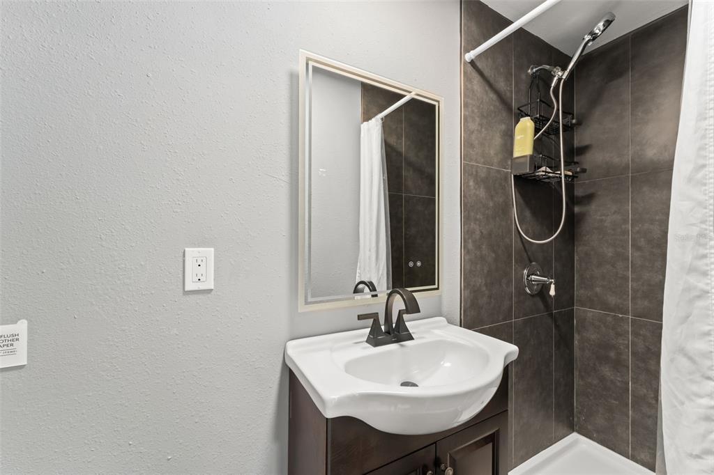 2223 Amherst Avenue Orlando, FL 32804 - Photo 62 of 64 a bathroom with a sink a mirror and a shower