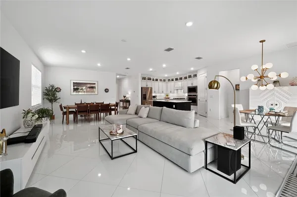 a living room with furniture kitchen view and a chandelier