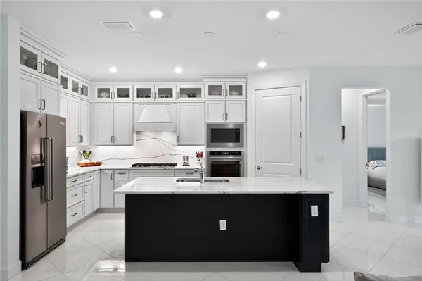 a kitchen with stainless steel appliances granite countertop a refrigerator a sink dishwasher and a stove with wooden floor