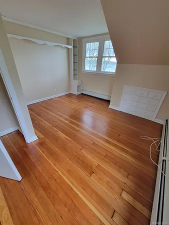 a view of empty room with window and wooden floor