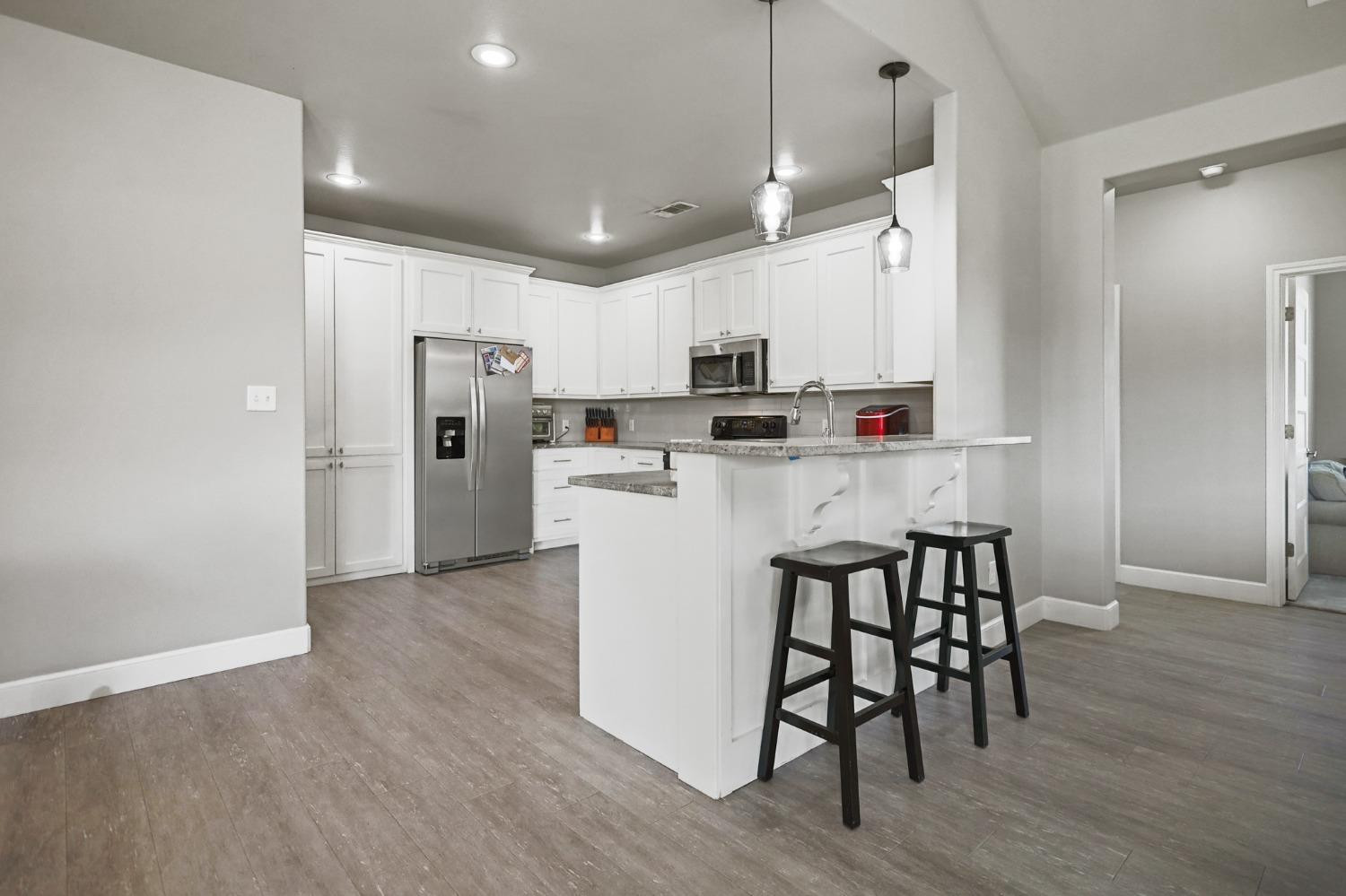 5227 Lehigh Street Lubbock, TX 79416 - Photo 11 of 33 a kitchen with kitchen island wooden floors white appliances and cabinets