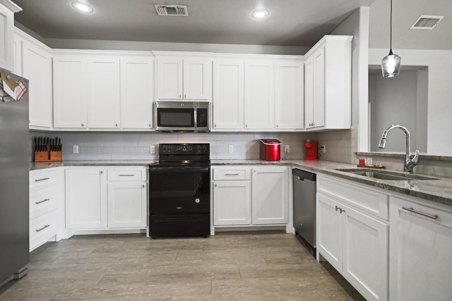 5227 Lehigh Street Lubbock, TX 79416 - Photo 12 of 33 a kitchen with white cabinets and black appliances