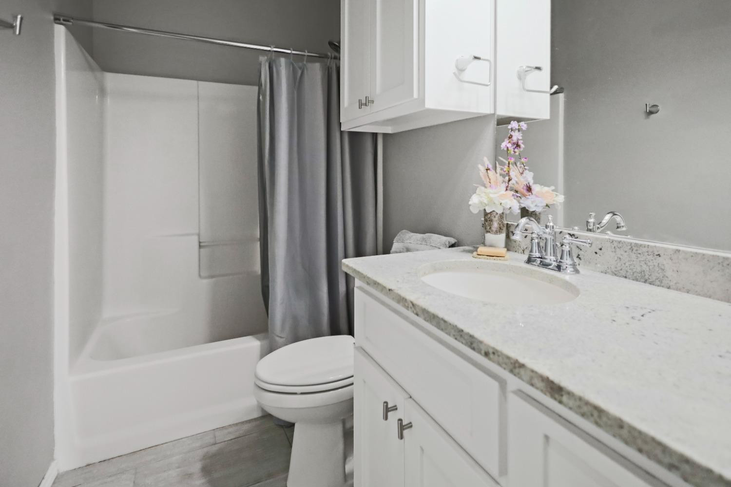 5227 Lehigh Street Lubbock, TX 79416 - Photo 18 of 33 a bathroom with a granite countertop sink a toilet and shower