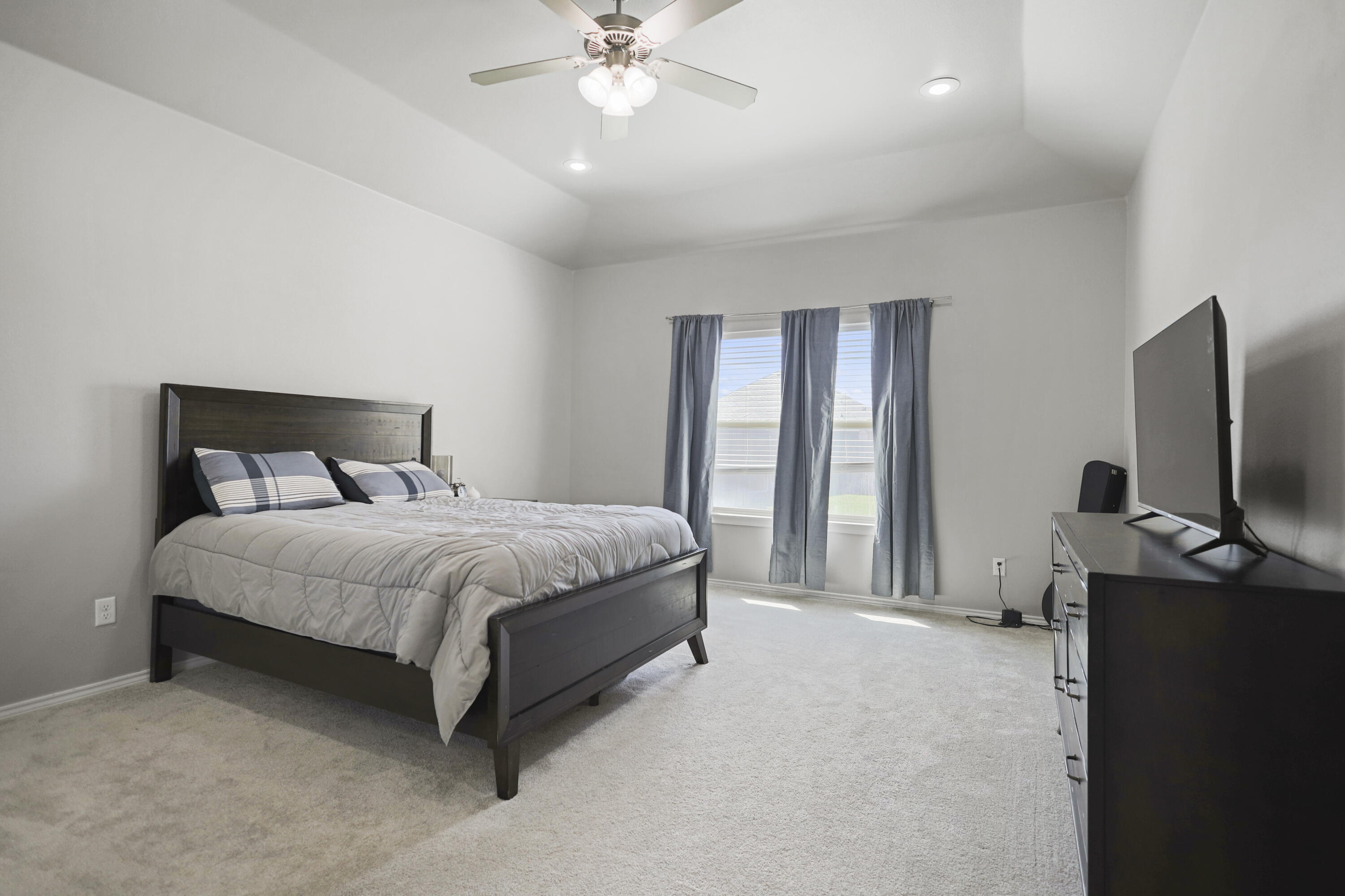 5227 Lehigh Street Lubbock, TX 79416 - Photo 19 of 33 a bedroom with a bed and a flat tv screen on dresser