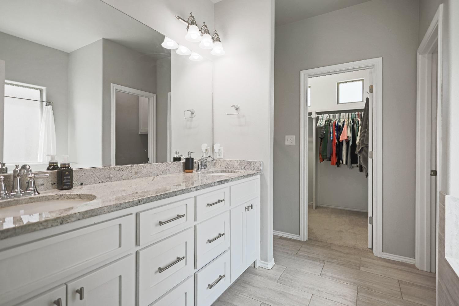 5227 Lehigh Street Lubbock, TX 79416 - Photo 21 of 33 a bathroom with a granite countertop sink two mirror and a