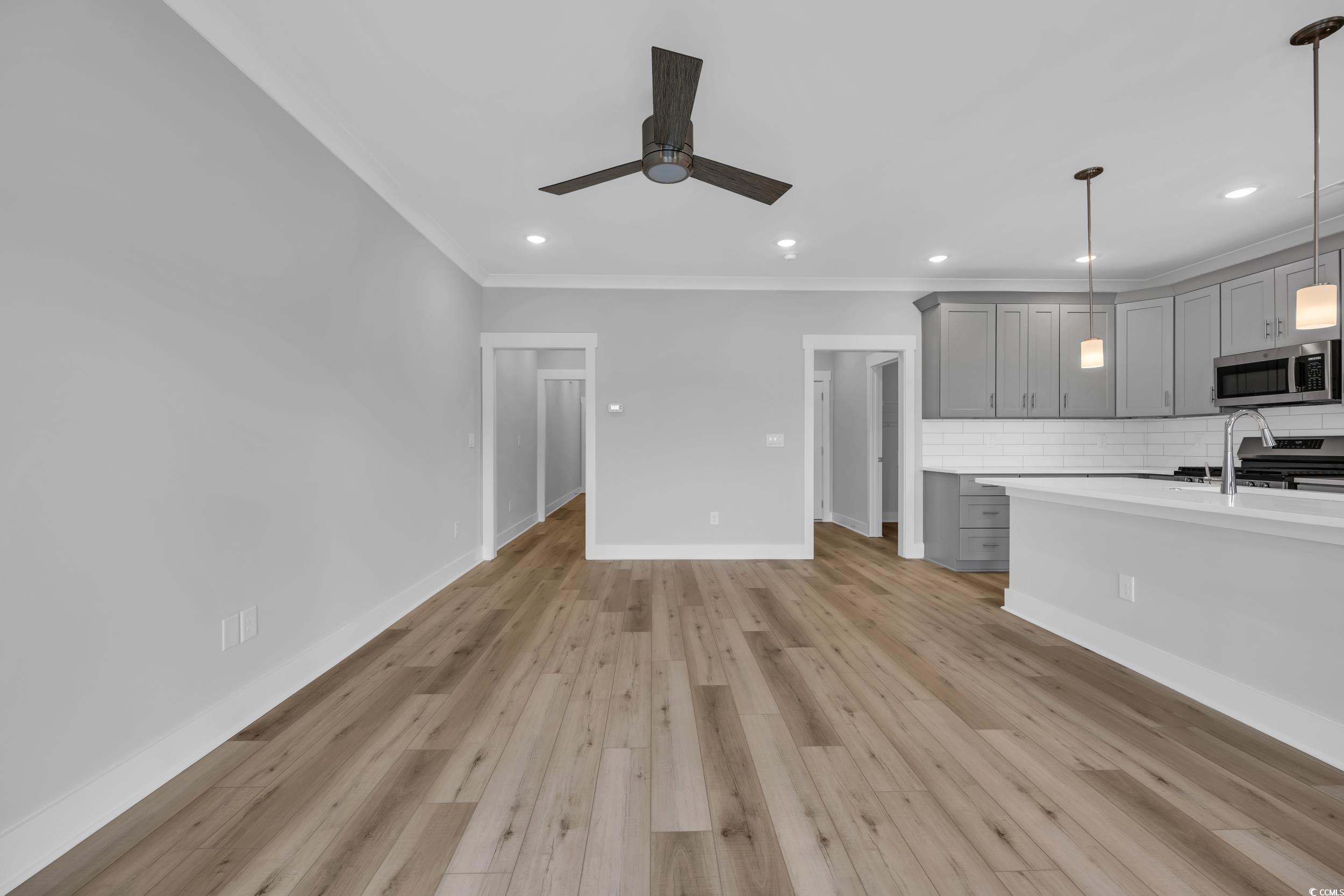 315 Lineback Place, Unit 37 Longs, SC 29568 - Photo 12 of 39 Unfurnished living room with baseboards, ornamental molding, ceiling fan, a sink, and light wood-style floors