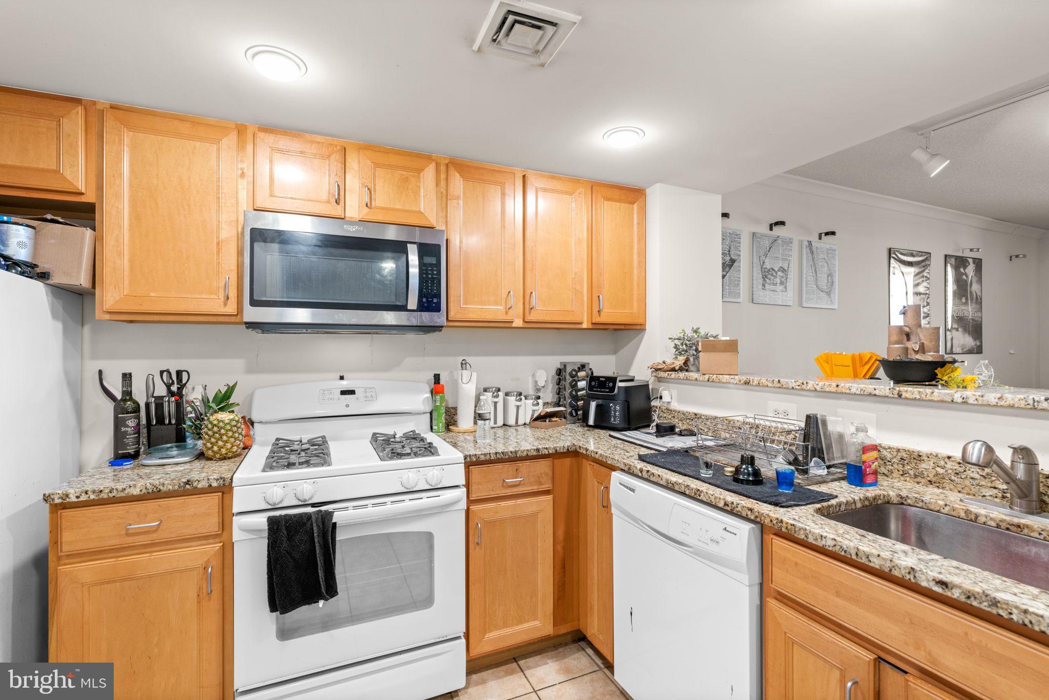 414 Water Street, Unit 2311 Baltimore, MD 21202 - Photo 17 of 44 a kitchen with stainless steel appliances a stove a sink a stove a microwave cabinets and a window