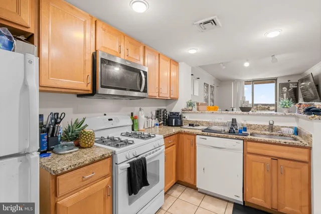 a kitchen with granite countertop a sink stove top oven and cabinets