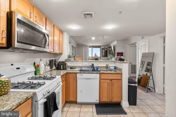 a kitchen with stainless steel appliances granite countertop a stove top oven a sink a refrigerator a counter top space and cabinets