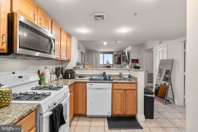 a kitchen with stainless steel appliances granite countertop a stove top oven a sink a refrigerator a counter top space and cabinets