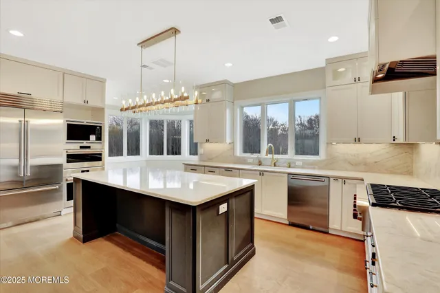 a large kitchen with kitchen island a stove a sink a center island and windows