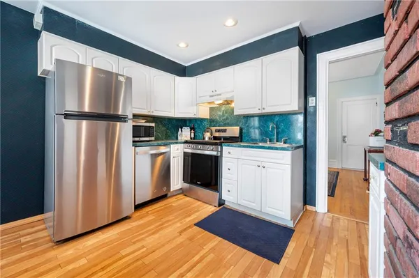 a kitchen with white cabinets stainless steel appliances and wooden floor