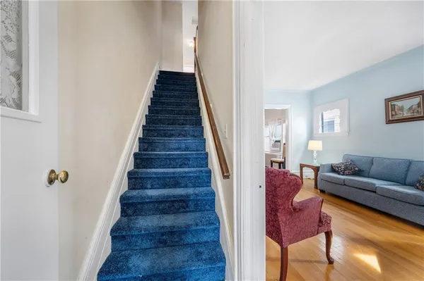 a hallway with wooden floor stairs and a couch