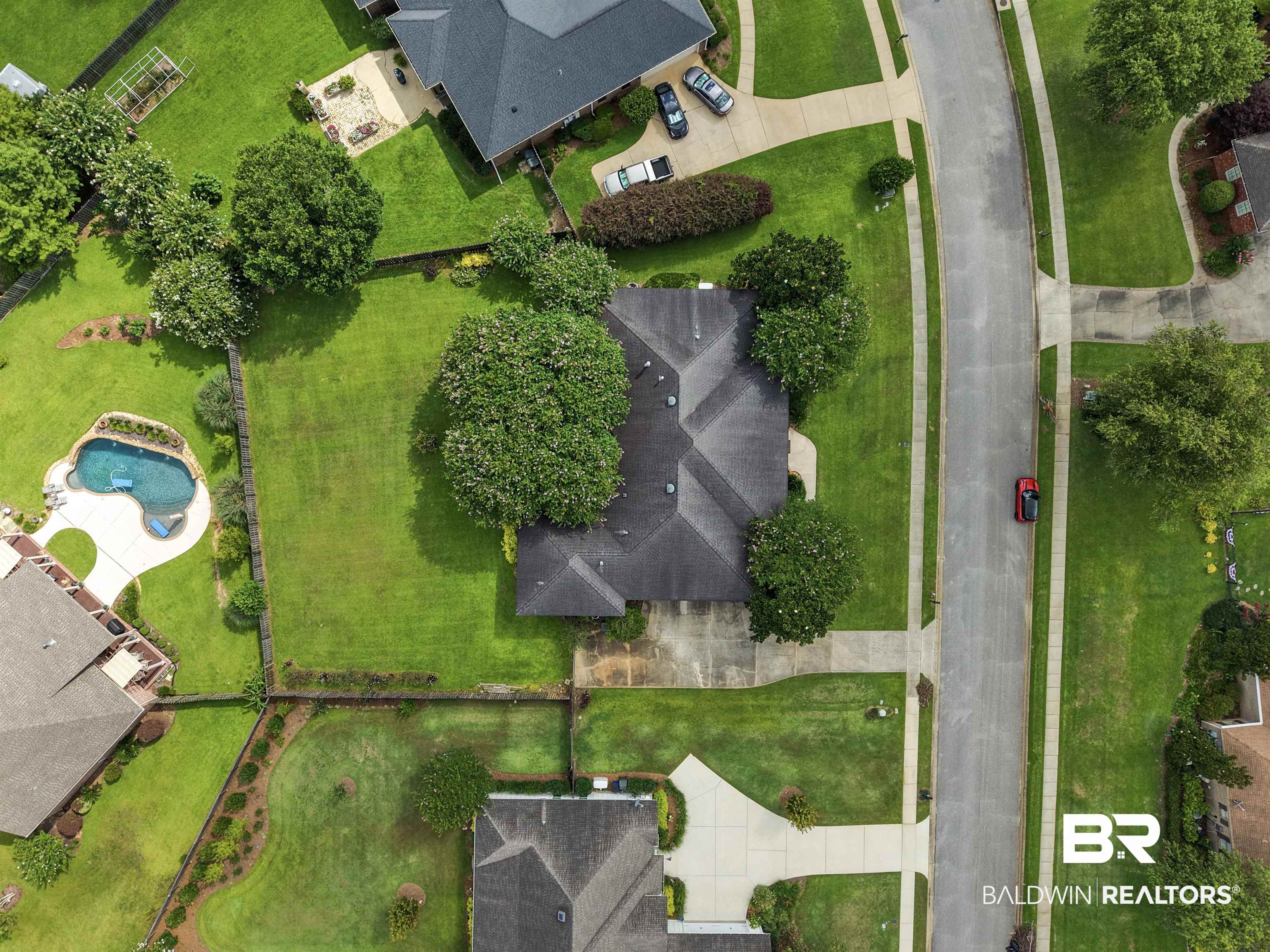 11261 Halcyon Loop Daphne, AL 36526 - Photo 40 of 41 Manicured property featuring a dark-toned roof, mature trees, and a concrete driveway