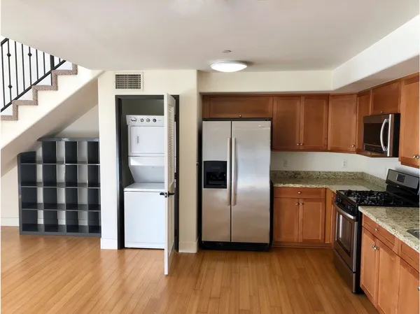 a kitchen with granite countertop a refrigerator and a stove top oven