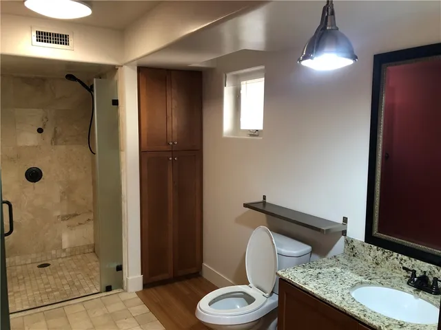 a bathroom with a granite countertop toilet and a shower