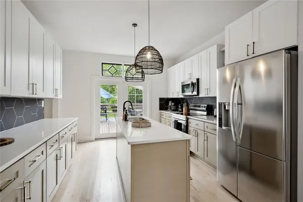 a kitchen with granite countertop stainless steel appliances a refrigerator a stove a sink cabinets and a dining table