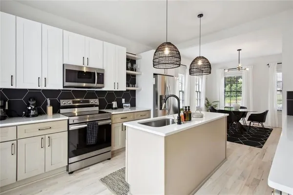 a kitchen with stainless steel appliances kitchen island granite countertop a sink a stove and a wooden floors