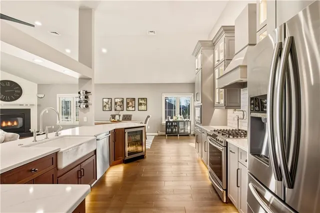 a kitchen with stainless steel appliances granite countertop a stove top oven a sink dishwasher a refrigerator and cabinets with wooden floor