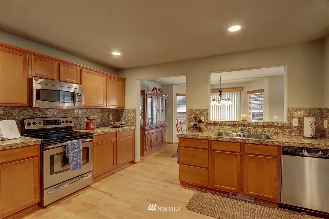 105 196th Place Southwest Bothell, WA 98012 - Photo 5 of 18 a kitchen with stainless steel appliances granite countertop a sink stove microwave and refrigerator