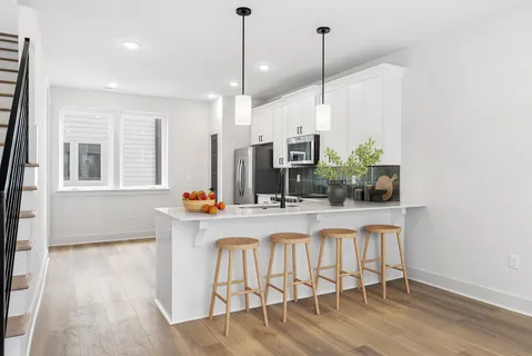 a kitchen with stainless steel appliances granite countertop a stove a sink and white cabinets with wooden floor