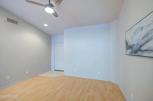an empty room with a ceiling fan and wooden floor