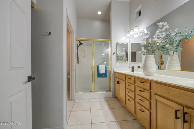 a spacious bathroom with a double vanity sink a large mirror and a shower
