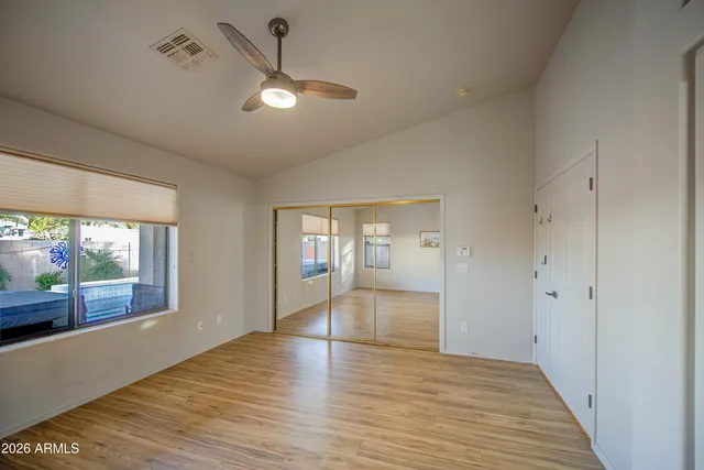 a view of empty room with wooden floor and fan