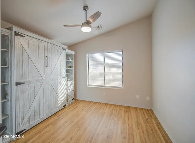 an empty room with wooden floor fan and windows