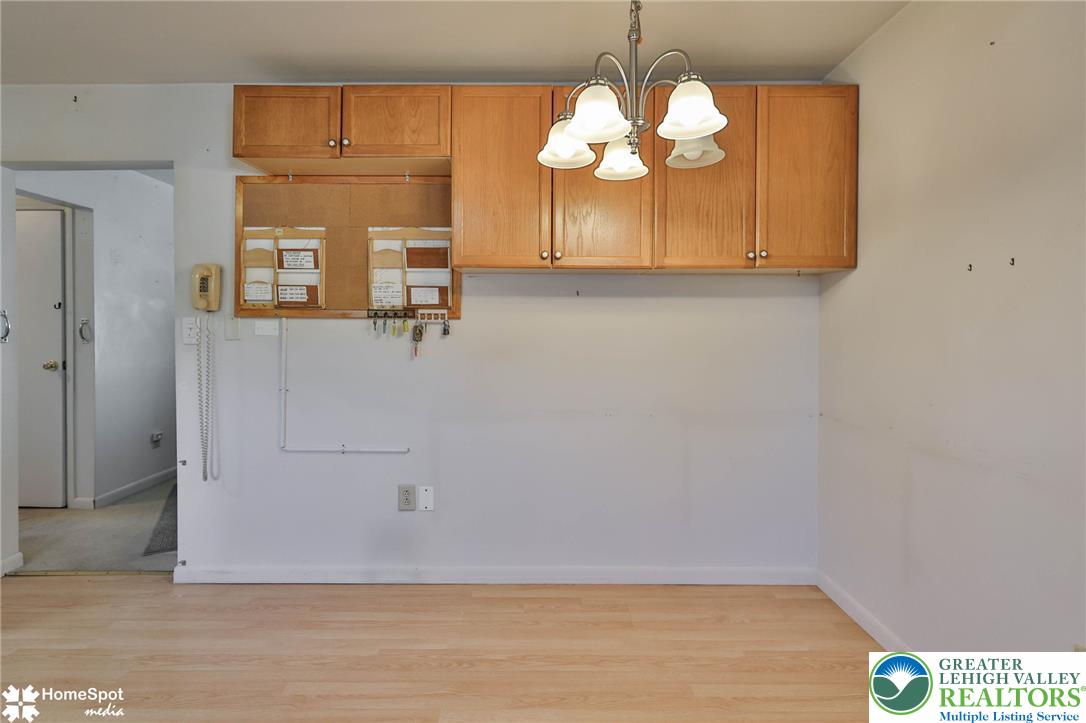 3069 Shakespeare Road Bethlehem, PA 18017 - Photo 13 of 50 Blonde wood flooring spans this versatile area, illuminated by a classic chandelier and offering functional overhead cabinetry.
