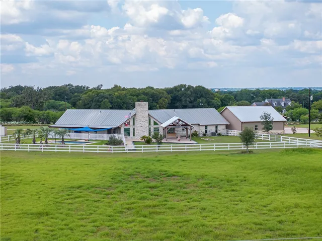a aerial view of a house with a big yard and large trees