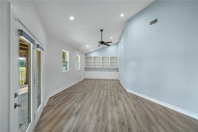 an empty room with wooden floor and windows