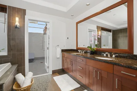 a spacious bathroom with a double vanity sink a large mirror and a shower