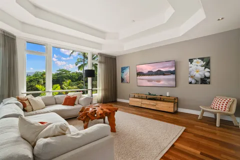 a living room with furniture floor to ceiling window and a flat screen tv