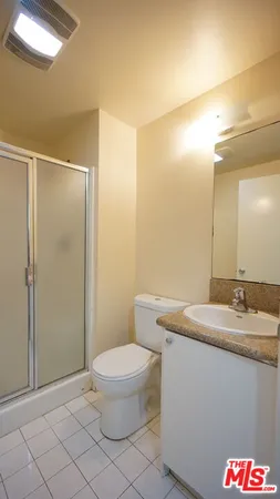 a bathroom with a granite countertop sink a toilet a mirror and shower