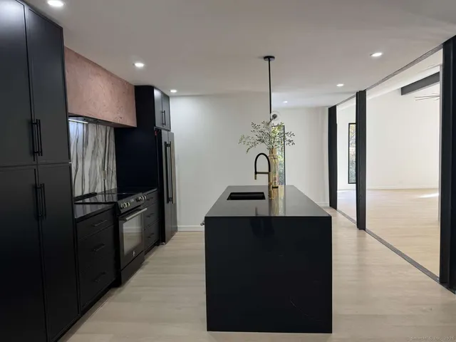 a kitchen with stainless steel appliances kitchen island granite countertop a refrigerator a stove and a sink with wooden floor