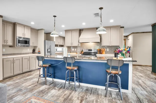 a kitchen with a dining table chairs wooden floor cabinets appliances and a window