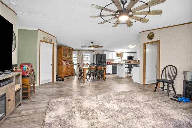 a view of a livingroom with furniture a chandelier a flat screen tv and a refrigerator