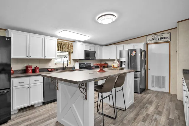 a kitchen with stainless steel appliances granite countertop a refrigerator a sink dishwasher a stove and white countertops with wooden floor