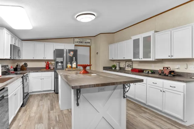 a kitchen with kitchen island granite countertop a sink cabinets and stainless steel appliances