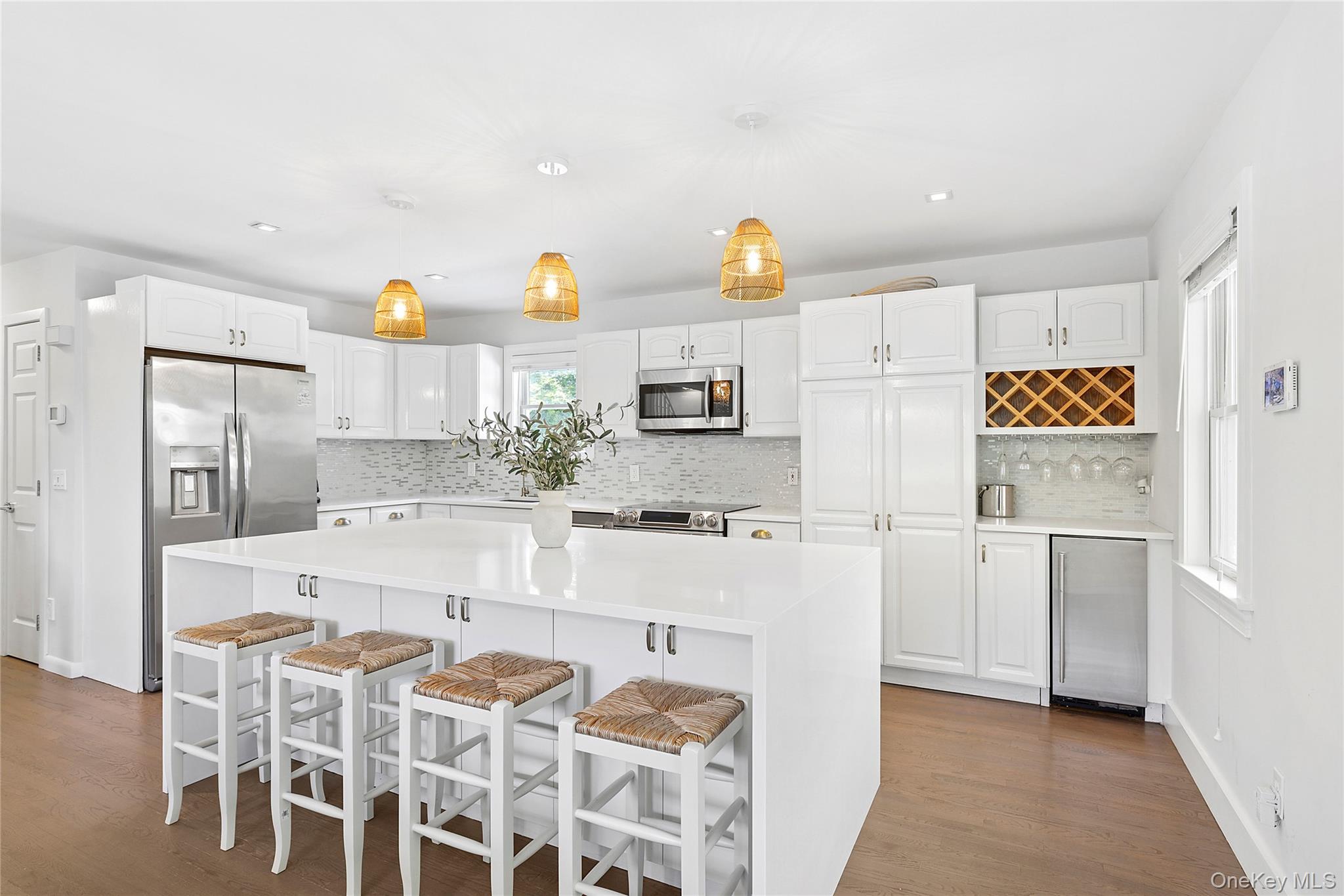 31 Highland Road Southampton, NY 11968 - Photo 3 of 19 Kitchen featuring pendant lighting, a breakfast bar area, white cabinetry, appliances with stainless steel finishes, and light stone countertops