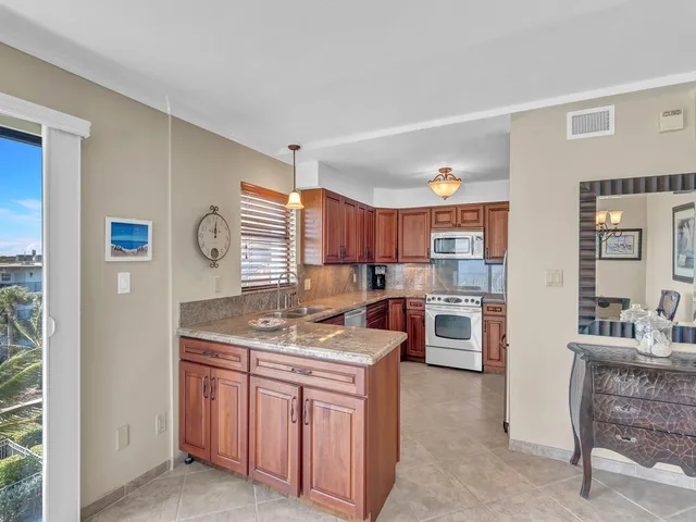 a kitchen with stainless steel appliances granite countertop a sink a stove and a wooden cabinets