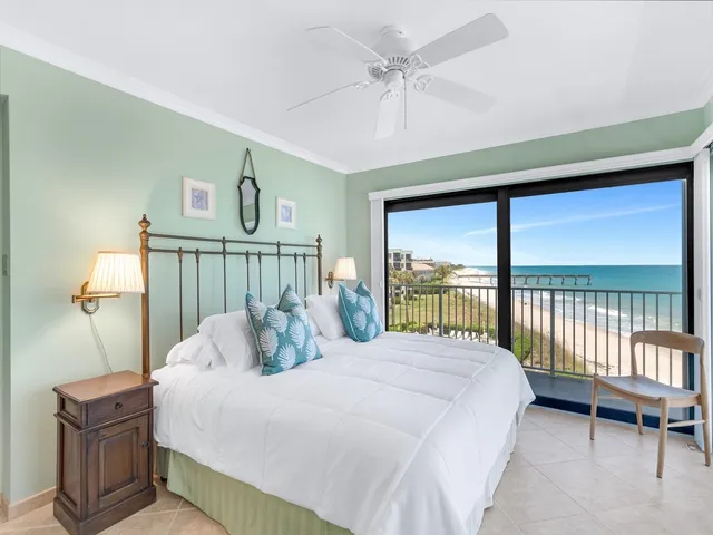 a large white bed in a room next to a window