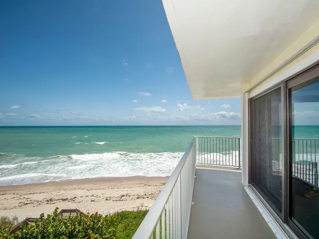 a view of a swimming pool with a lawn chairs under an umbrella