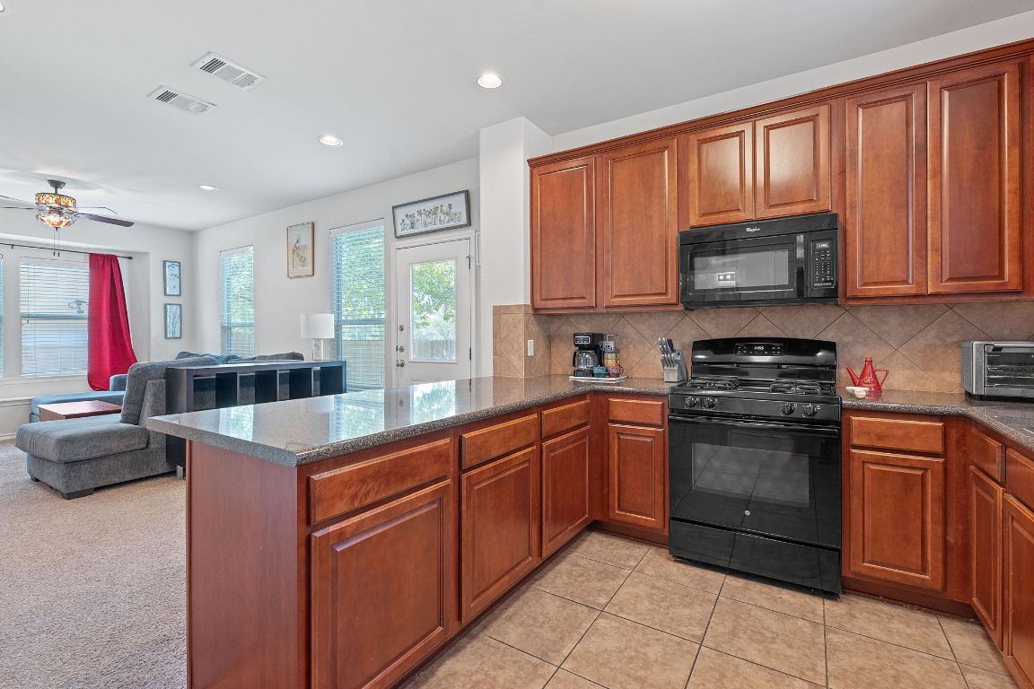 10700 Macmora Road, Unit 116 Austin, TX 78758 - Photo 26 of 26 Kitchen featuring black appliances, a peninsula, tasteful backsplash, open floor plan, and recessed lighting