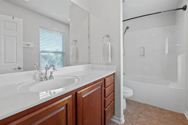 a en suite bathroom with a granite countertop sink and a large mirror