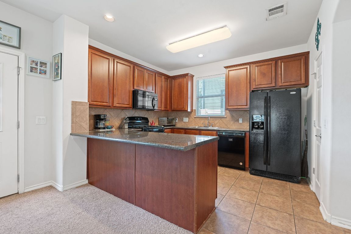 10700 Macmora Road, Unit 116 Austin, TX 78758 - Photo 8 of 26 Kitchen featuring a peninsula, decorative backsplash, black appliances, dark stone countertops, and recessed lighting