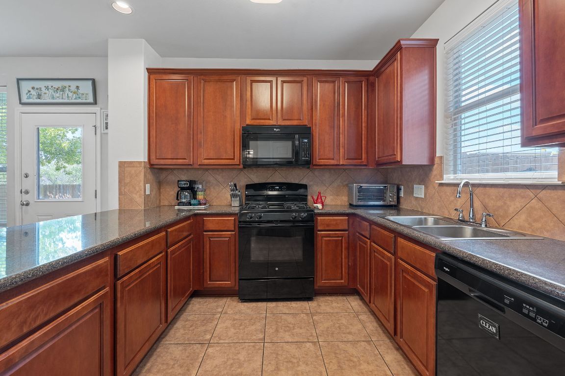 10700 Macmora Road, Unit 116 Austin, TX 78758 - Photo 10 of 26 Kitchen featuring black appliances, tasteful backsplash, light tile patterned flooring, brown cabinetry, and recessed lighting